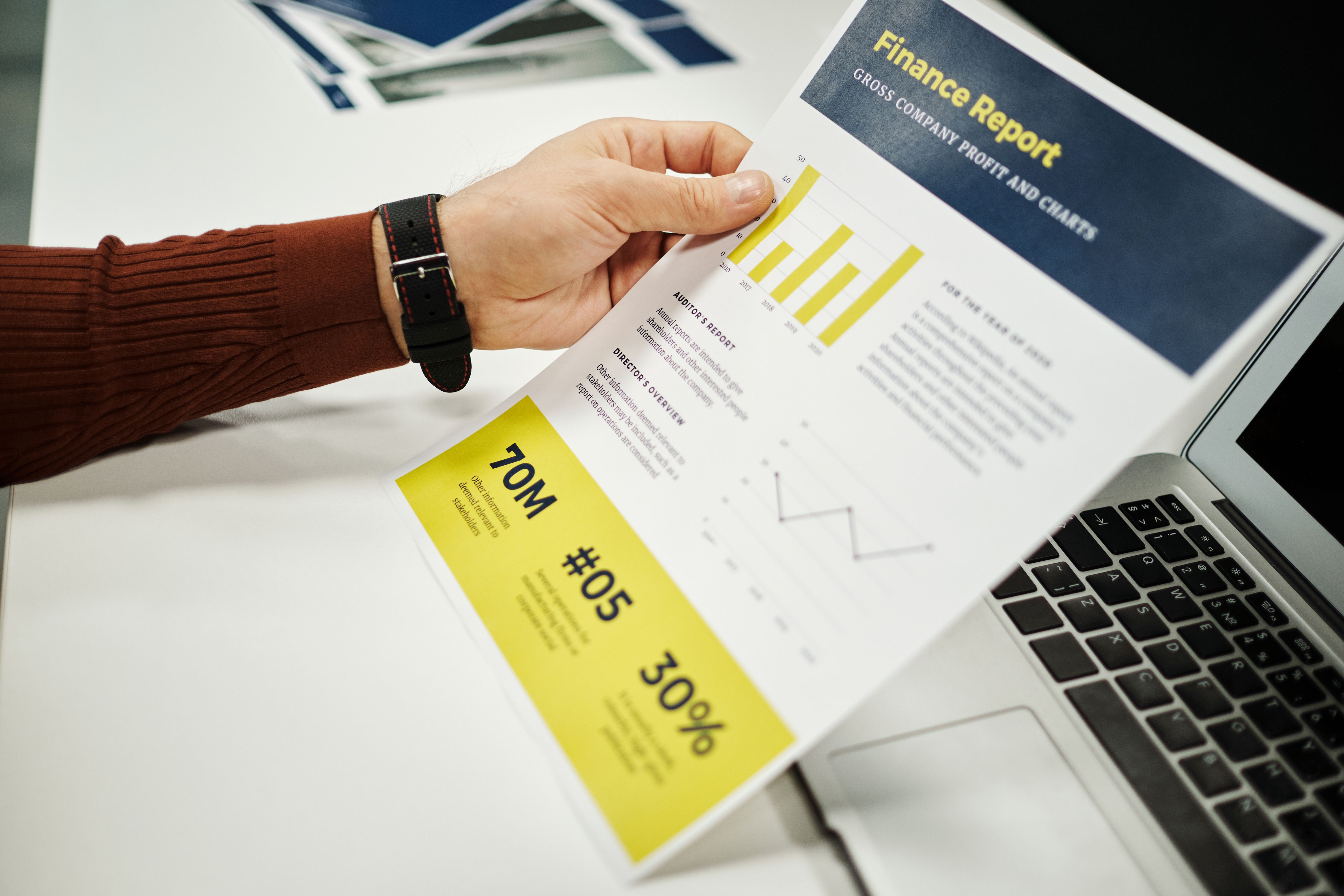 Business owner reviewing a financial report next to a laptop